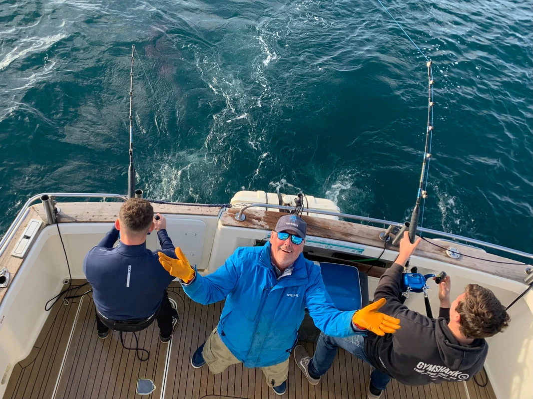 Anglers and crew on True Blue’s fishing deck with open sea behind them